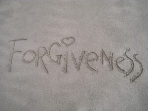 The word 'forgiveness' written in sand
