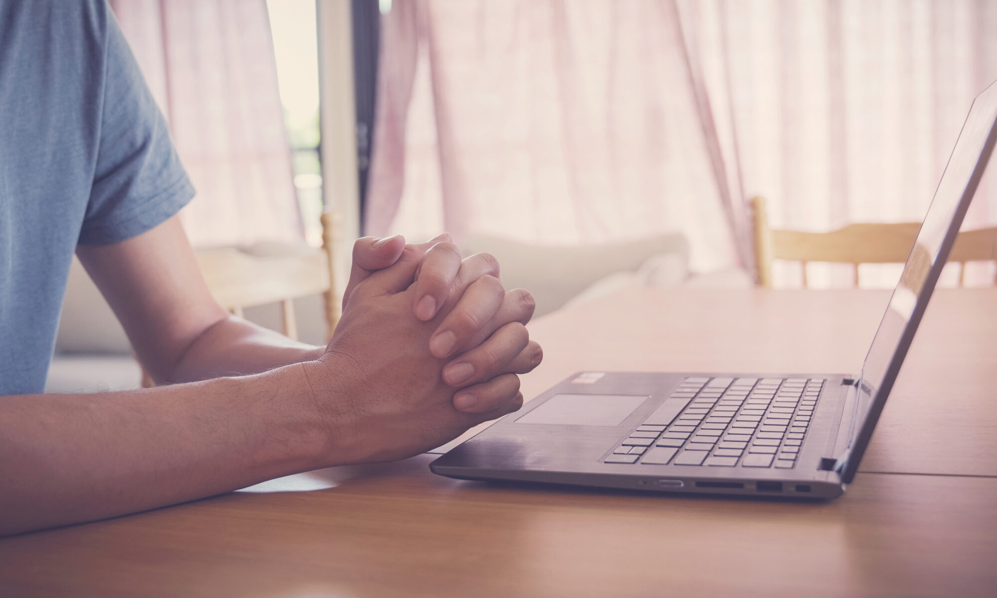 Praying hands with a laptop