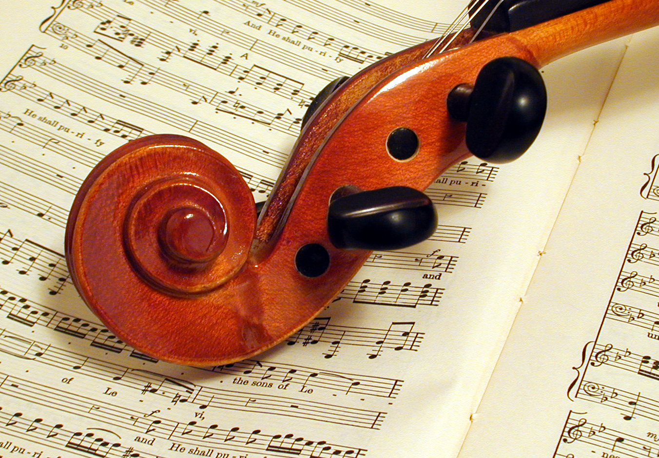 The tuning portion of a violin laying atop sheet music from Handel's 'Messiah.'