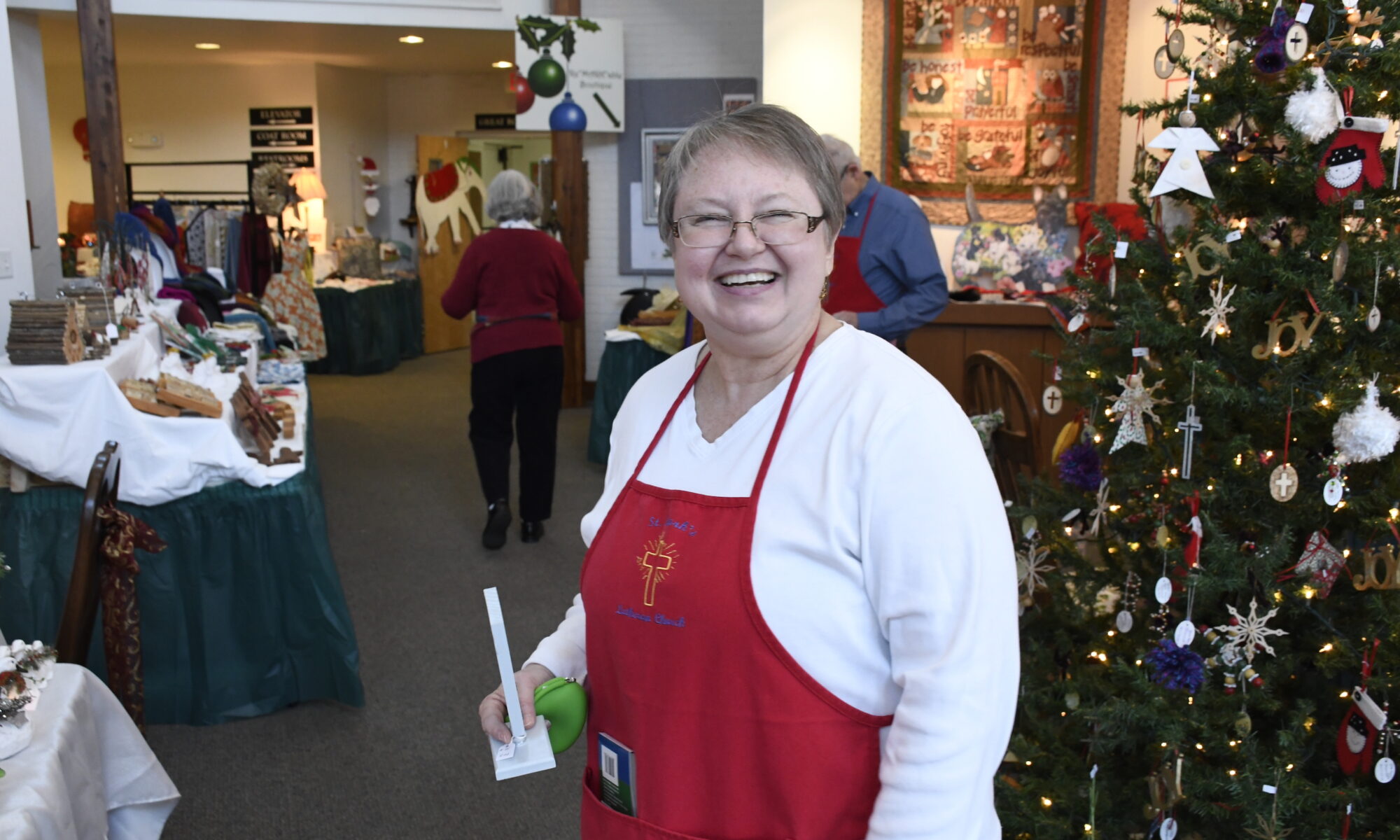 A Christmas Bazaar volunteer holding a candle in the main lobby at St. Mark's.